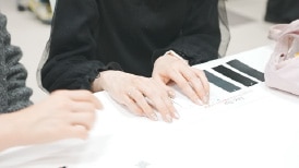 商品タグのサンプルを視覚障害者が触って比較している様子。