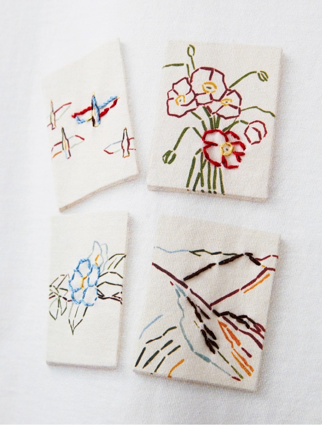 画像：鳥、ポピー、山、ツバキを描いたアート作品のフォトプリントをあしらったカットソーのアップ　画像おわり