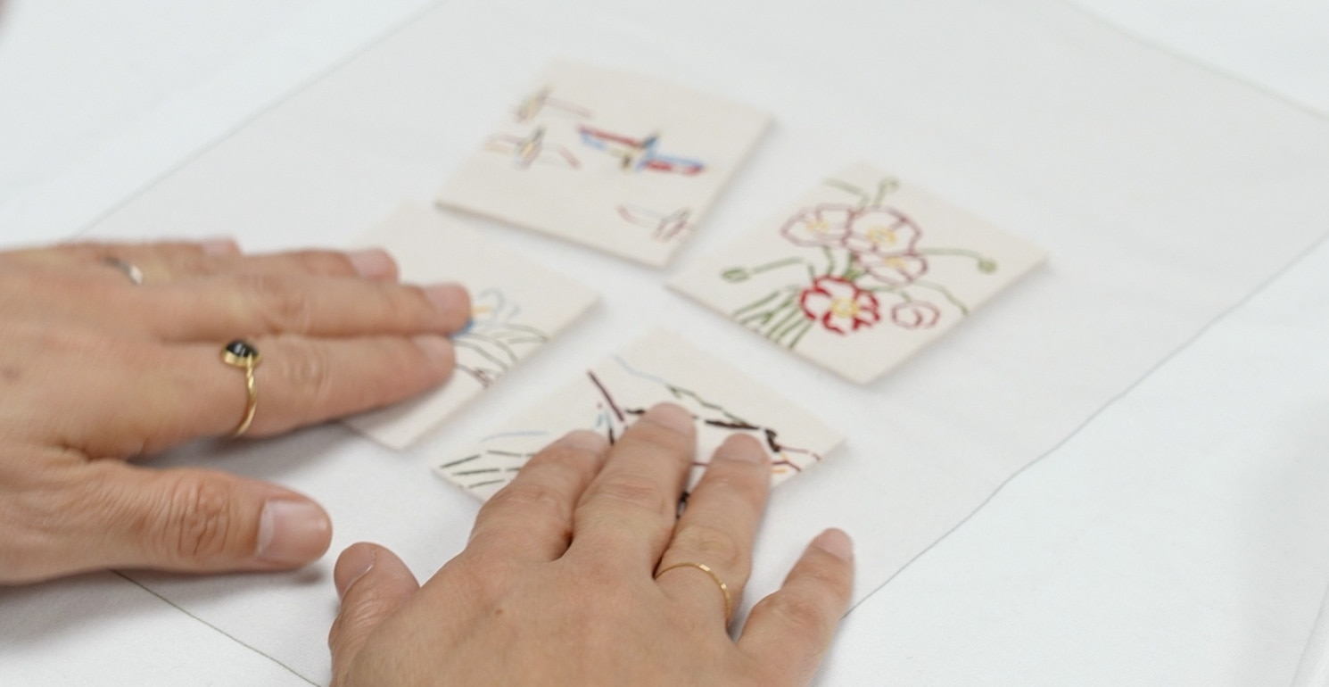 画像　刺繍が施された白いTシャツに触れる手のアップ　画像おわり