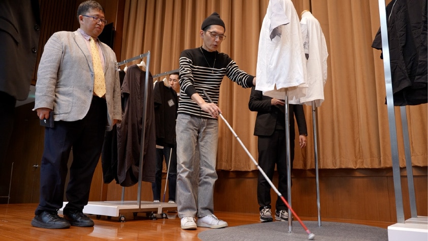 画像：売場をイメージした会場でブラインド・コミュニケーターが購入体験をしている様子　画像おわり