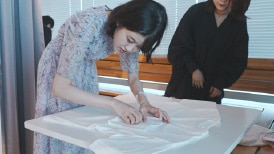 画像:視覚障がい者の女性がカットソーのサンプルに触れ、風合いなどを確かめている様子。 画像おわり