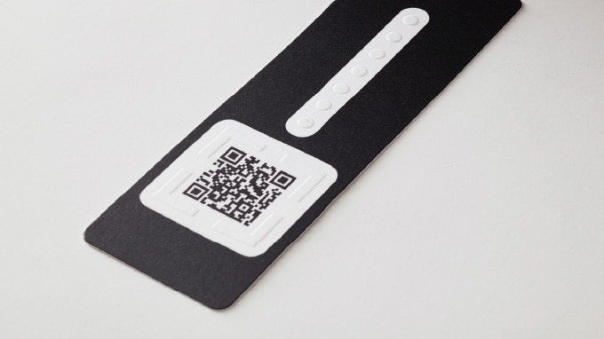 画像:二次元コードの場所が触って分かるように凹凸加工された商品タグの画像。 画像おわり