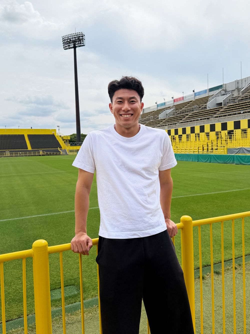 日立台のピッチを背景に観客席に立つ細谷真大選手
