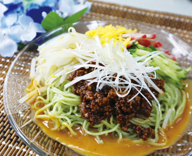 ひき肉や白髪ねぎ、キュウリなどの具材が乗っている冷やし麺の画像