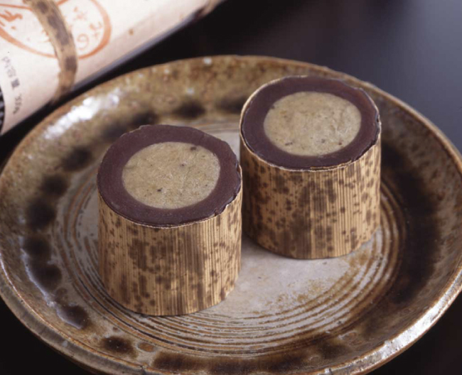 栗きんとん包んだ羊羹を竹皮で包んだ和菓子の写真