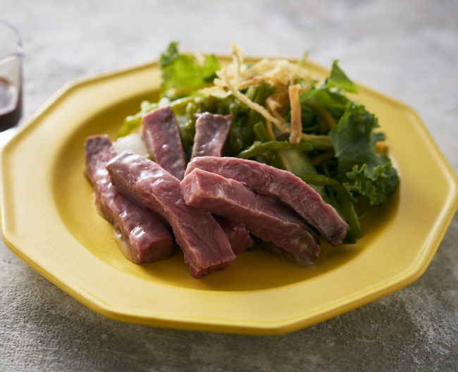拍子切りした牛肉と葉物野菜を皿に盛り付けたイメージ画像