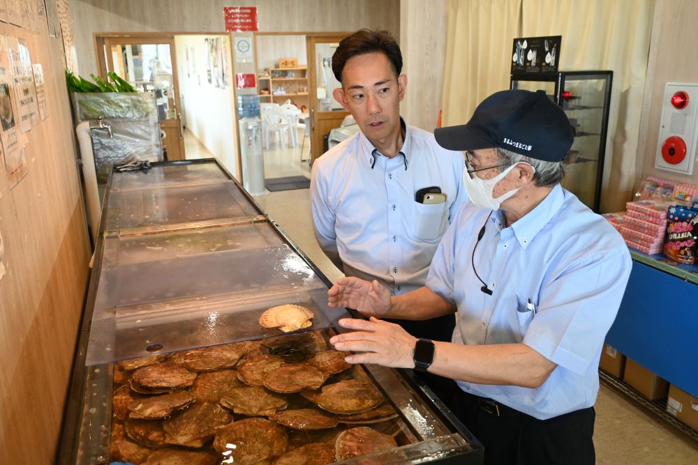 さるふつまるごと館の小松孝喜さんから、ほたてについてお話を伺う様子