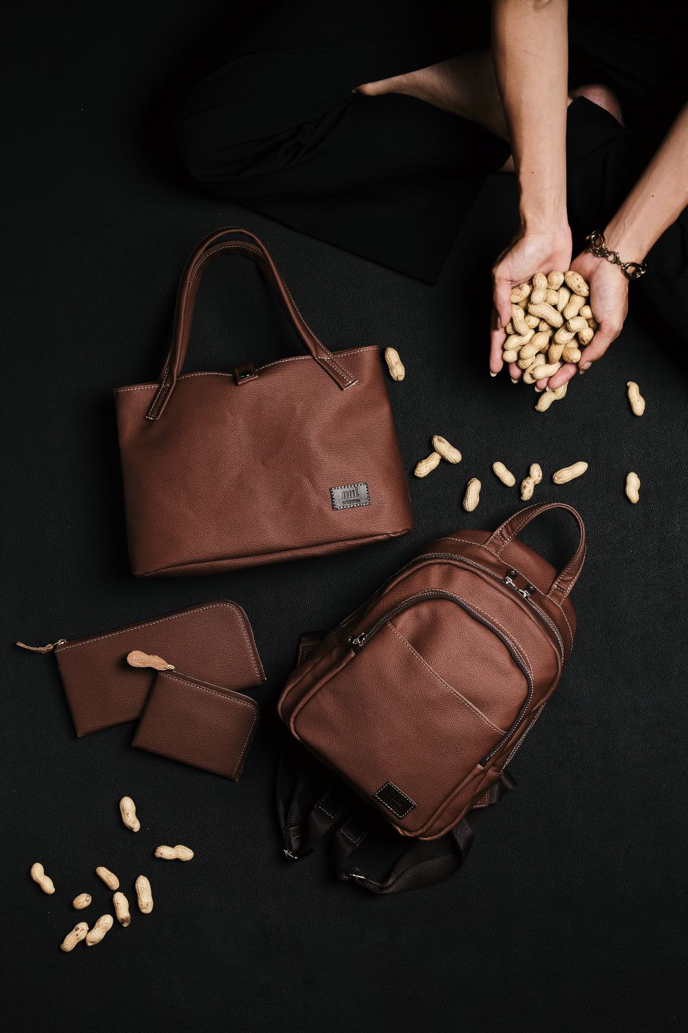 ピーナッツレザーで作られたバッグやリュック、財布が並べられ、周りに落花生が散りばめられている様子