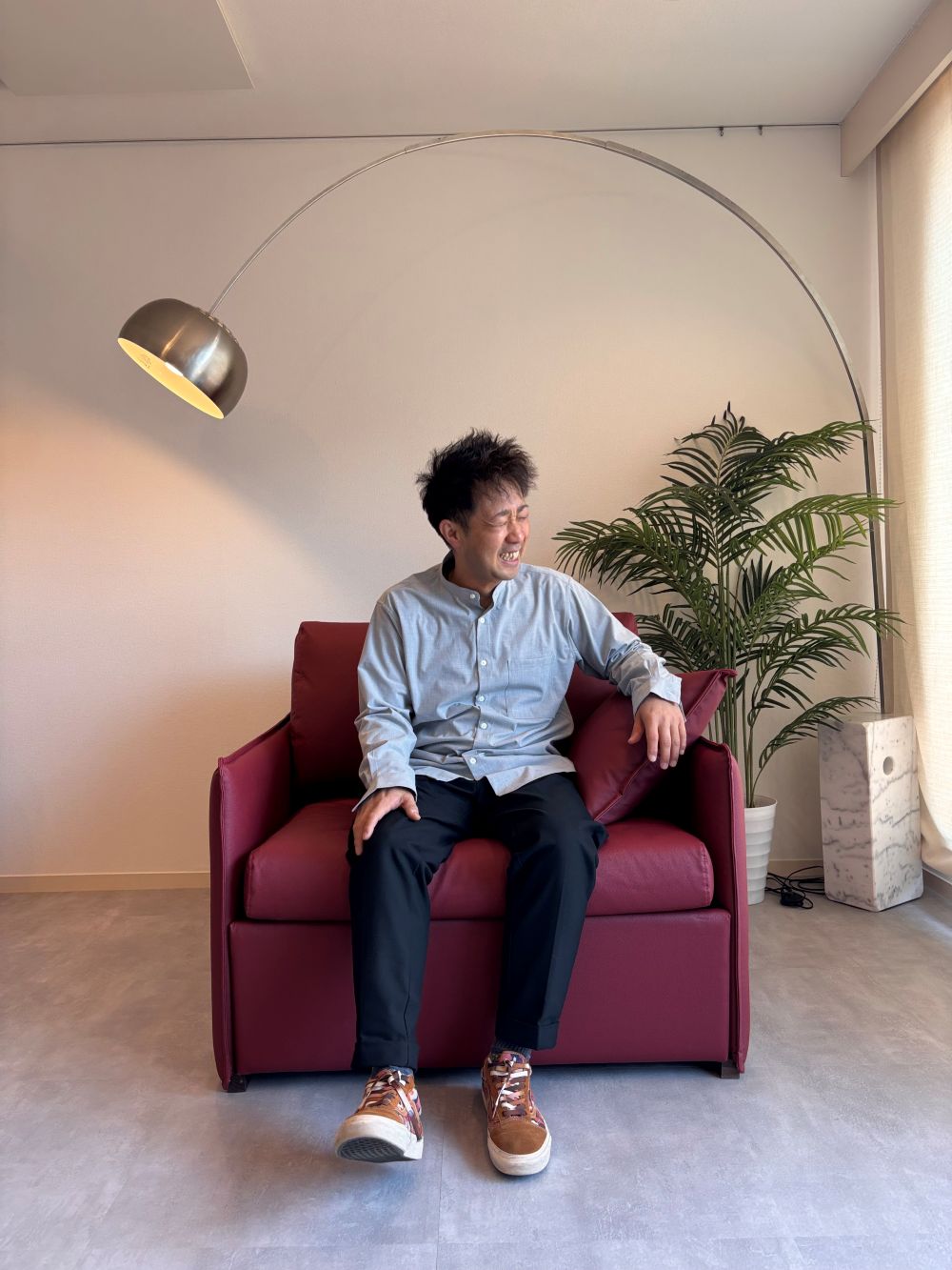 ピーナッツレザーを生地に使ったソファに座り、嬉しそうに笑う柏レザー株式会社代表の飯島さん