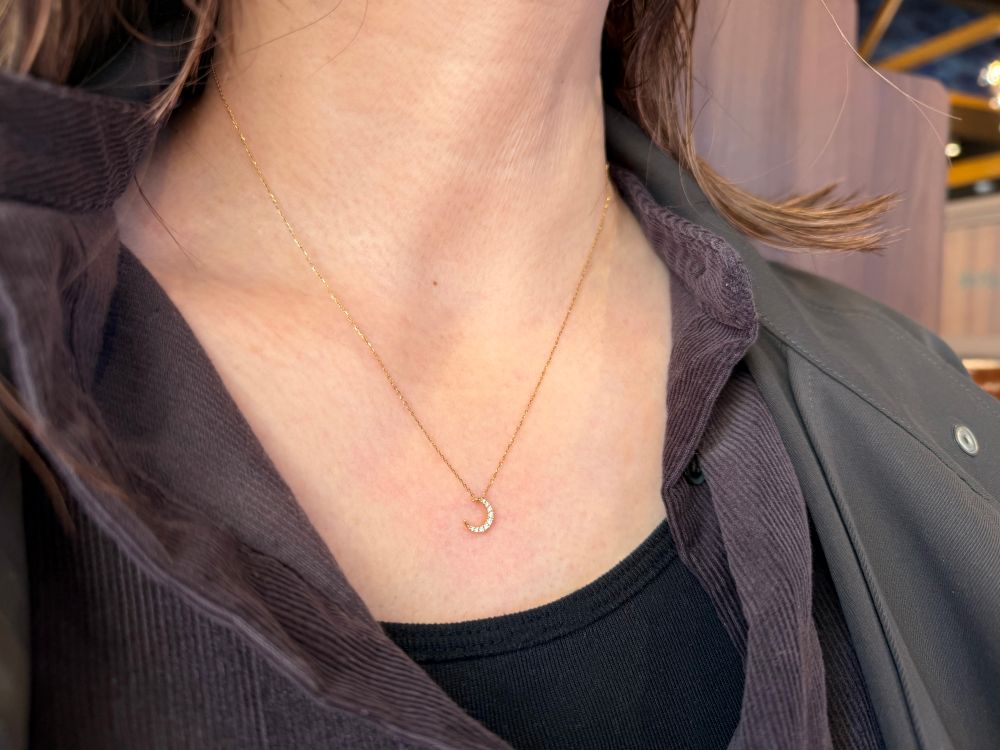 細いゴールドのチェーンに、小さな三日月形のペンダントがついたスタージュエリーのネックレス