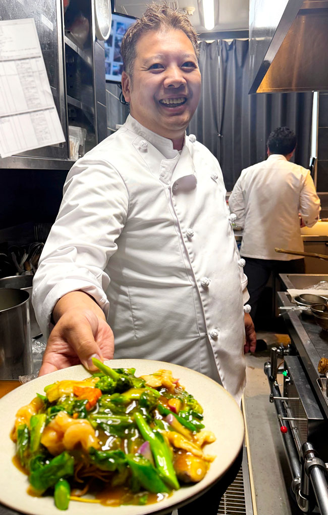 中国料理 文菜華の厨房で出来立てのかた焼きそばを笑顔で差し出す渡辺シェフ