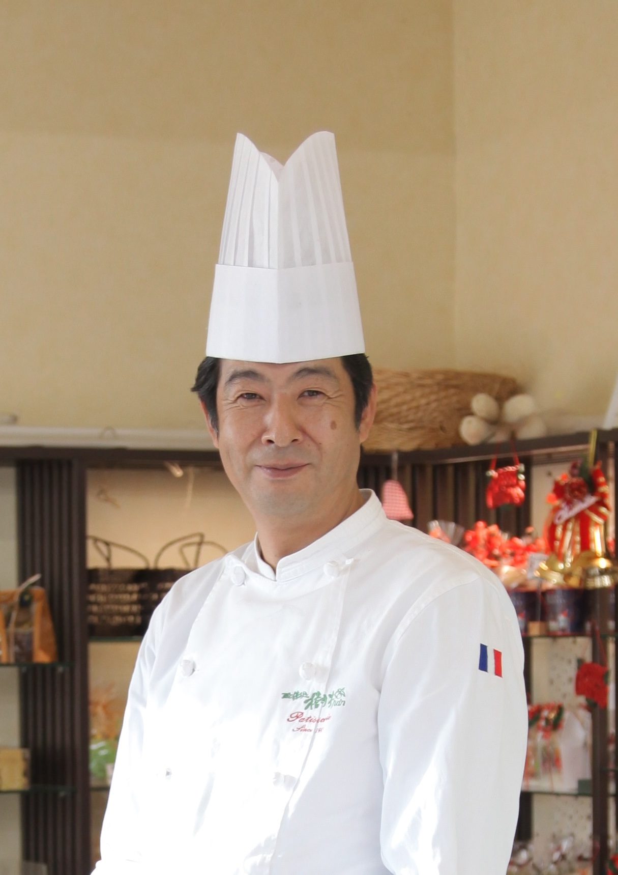 コックシャツとコック帽を身につけ笑顔の古田さんプロフィール写真