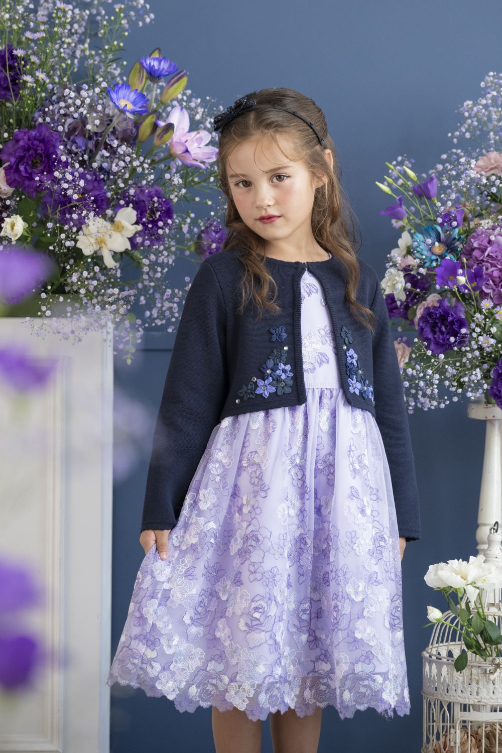 レースのワンピースとネイビーのニットジャケットを着用した女の子