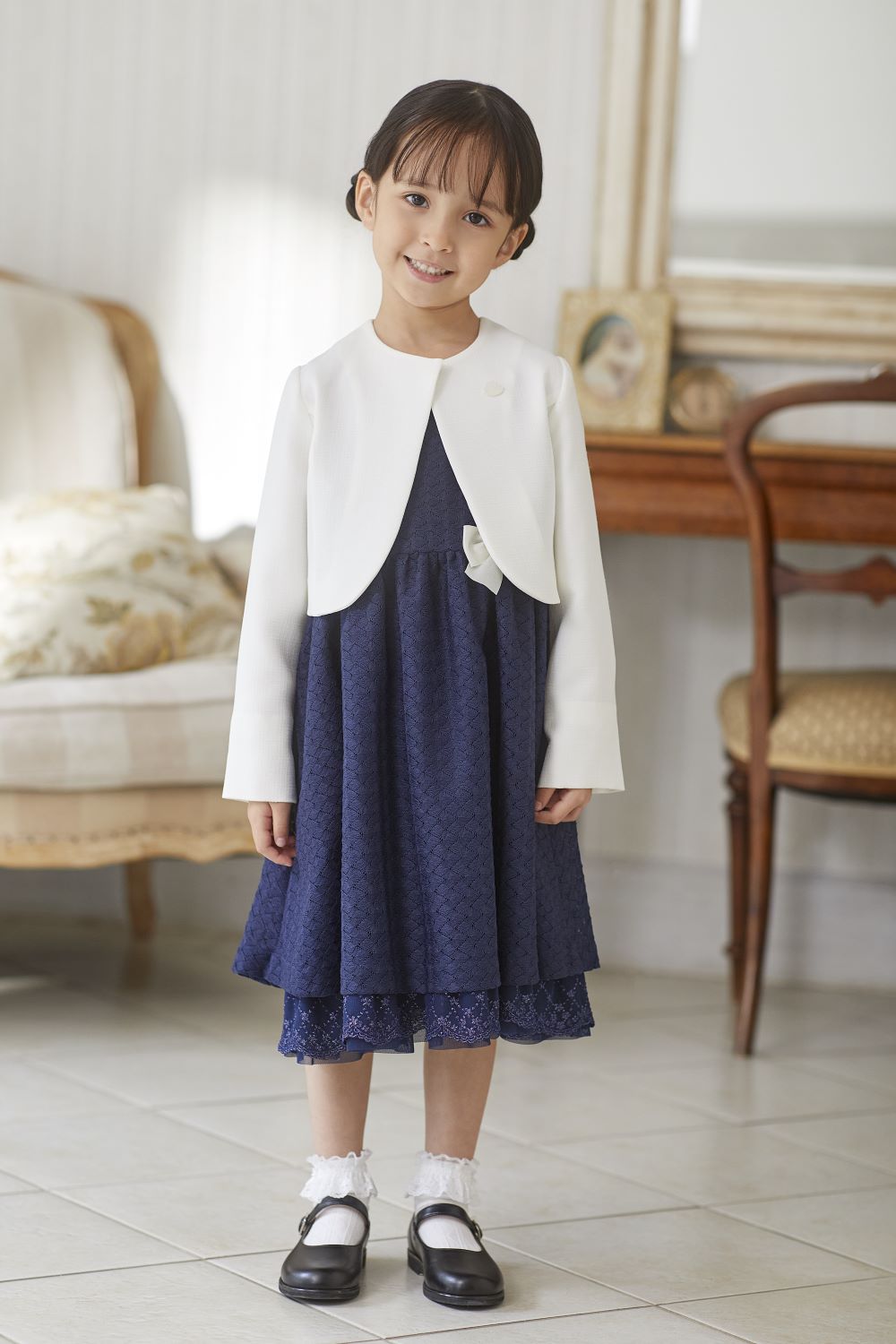 白いジャケットとネイビーのワンピースを着用した女の子