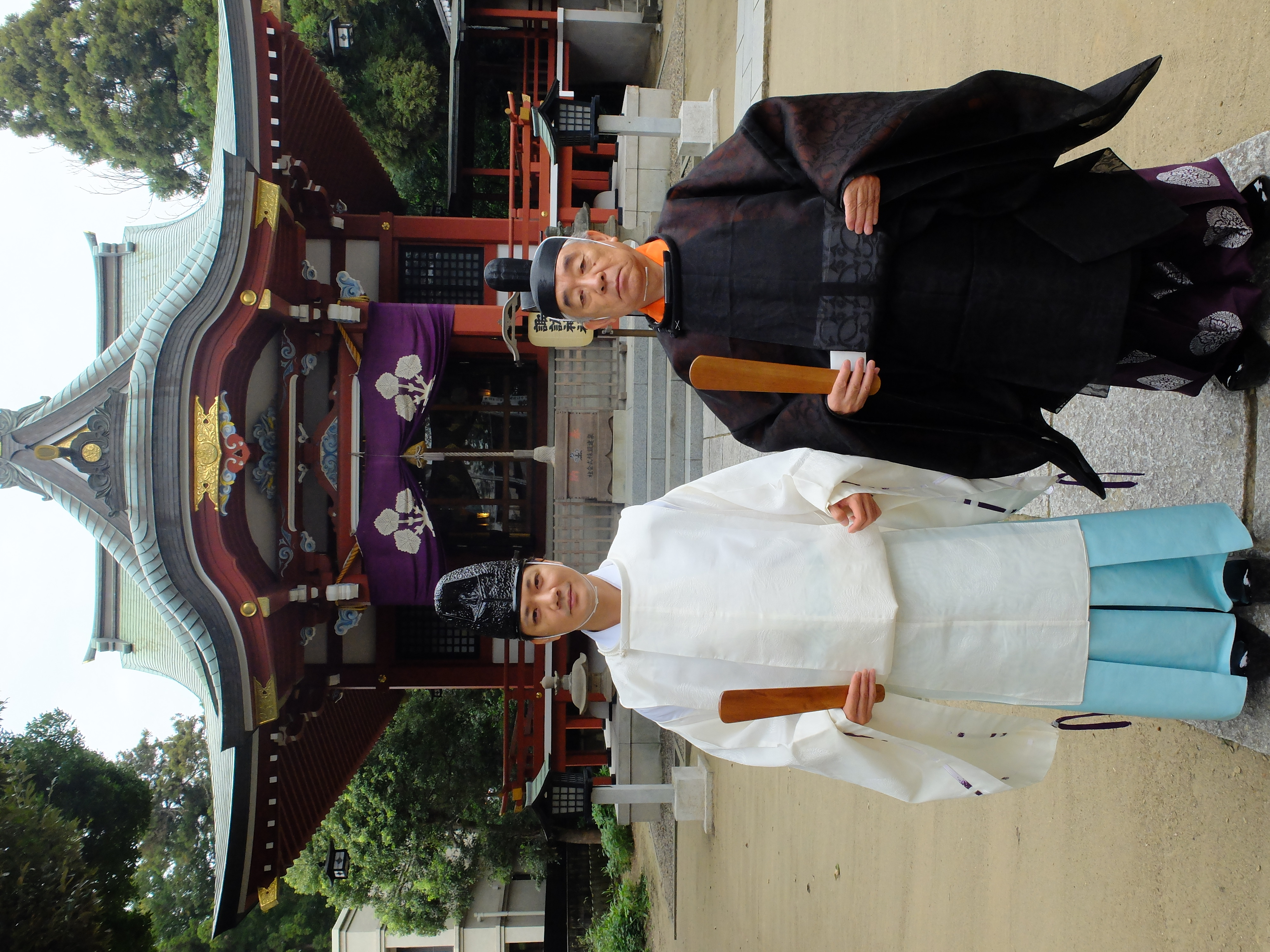 柏神社の前で宮司の衣装を身につけて記念撮影をする友野さんと父の先代宮司