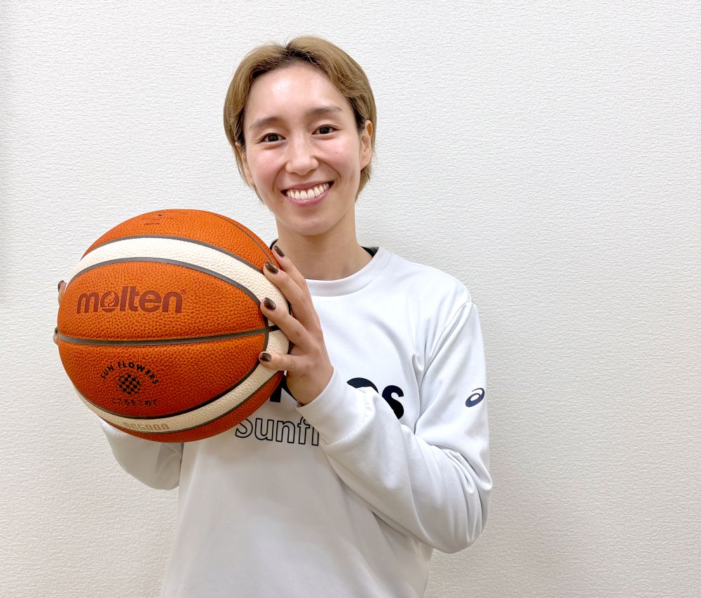 バスケットボールを顔の近くに持ち、カメラに向かって微笑むENEOSサンフラワーズ所属の宮崎早織選手