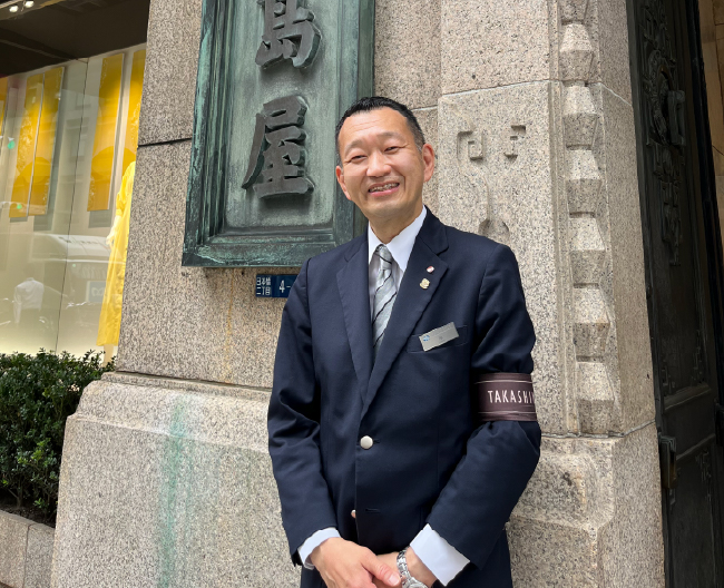 日本橋高島屋S.C.本館の前に立つコンシェルジュ・岸和彦の写真