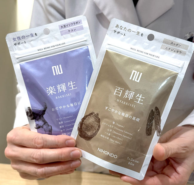 漢方ブティックの岩田店長が輝生（きせい）シリーズの百輝生（ひゃっきせい）と楽輝生（らっきせい）を持つ手元の様子