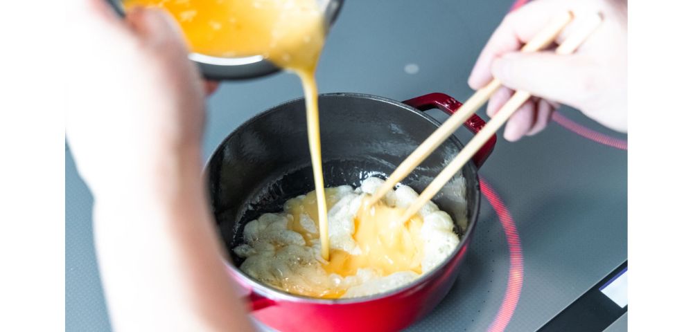 油が温まったら菜箸でゆっくりかき混ぜながら卵液を一度に注ぐ。半熟状態になったら、蓋をして弱火で1分加熱する。