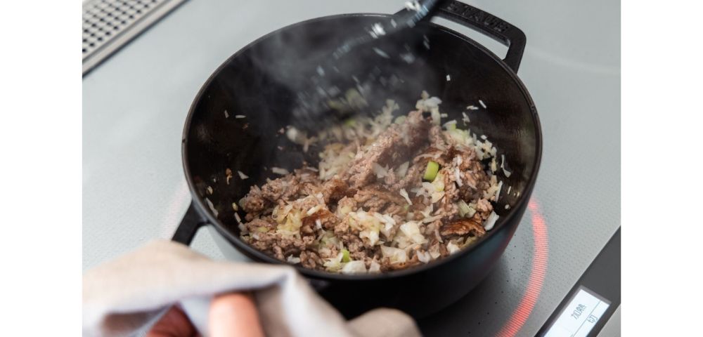 ワナベを中火で予熱しておき、サラダ油を引いたら豚ひき肉をひろげ、焼き目をつける。長ネギを加えてさらに炒める。